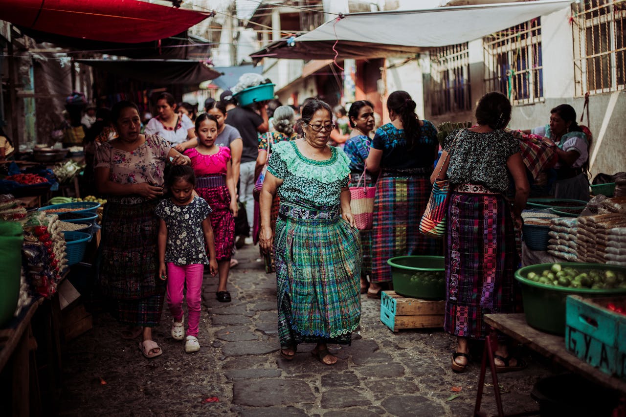 services-03 Women and children in colorful traditional dresses at a bustling Guatemalan market.