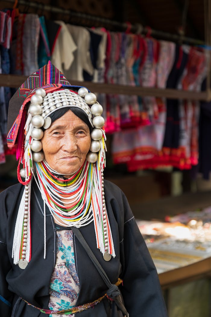 Senior Akha woman in traditional attire at a market in Chiang Rai, Thailand.