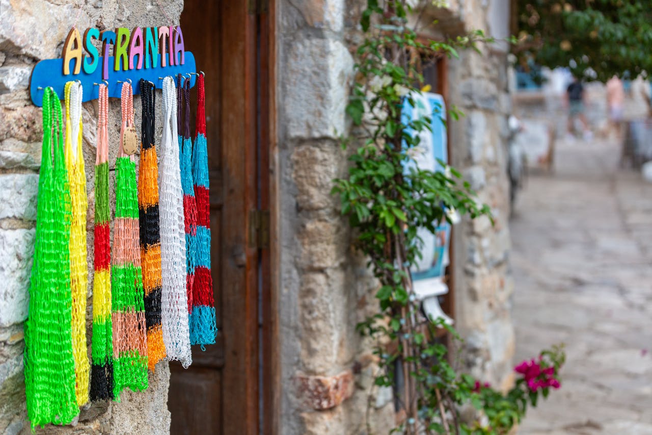 services-02 Vibrant handmade nets displayed outside a rustic stone building, showcasing artisanal craftsmanship in a quaint village setting.