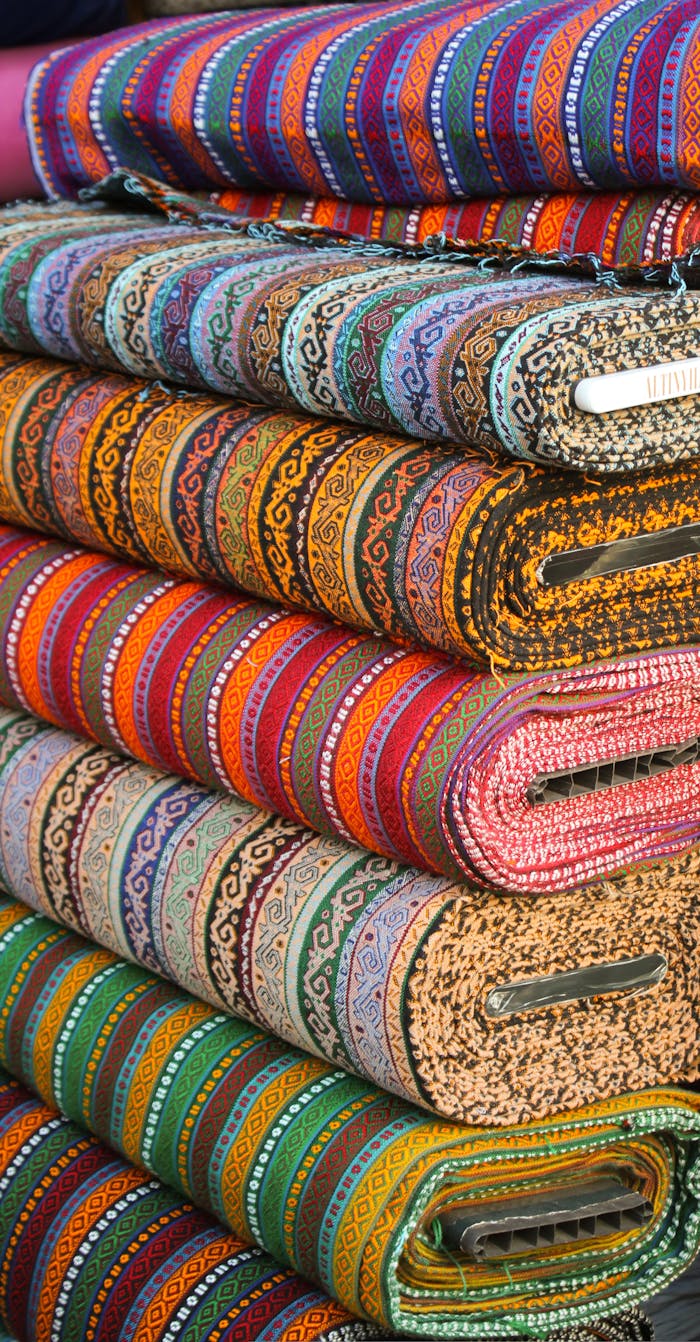 who-we-are Vibrant stacked textiles with intricate ethnic patterns, showcasing diverse colors.